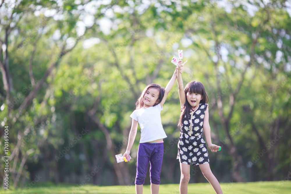 Fototapeta premium Two little girls relaxing play in the park and eat lollipops