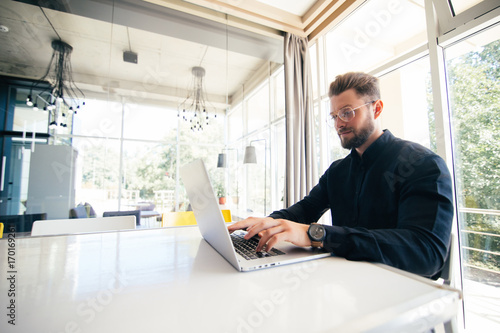 Handsome businessman working with laptop in modern bright office