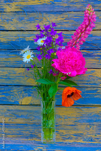 Букет цветов в вазе на фоне старой досчатой стены.