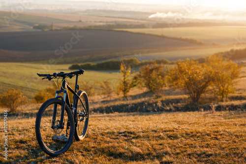 Silhouette of a bike on the hills at sunset.