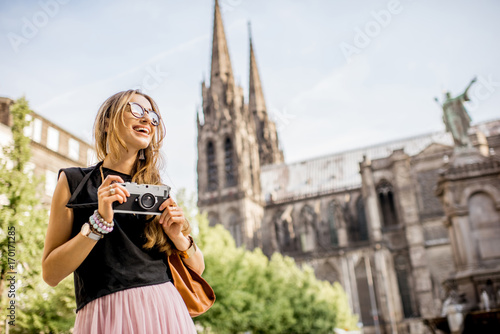 Portrait of a woman with photo camera traveling in front of the famous cathedral in Clermont-Ferrand city in France
