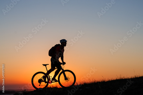 Silhouette man stand with mountain bike on the meadow
