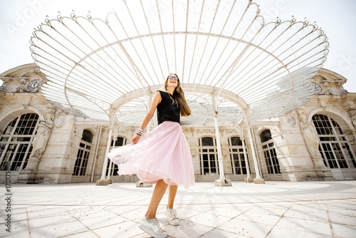 Lifestyle portrait of a woman in skirt spining near the beautiful old opera building in Vichy city in France