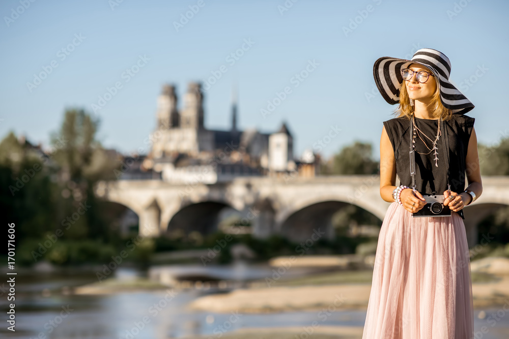 Young woman tourist standing on the beautiful cityscape background during the sunset in Orleans city, France