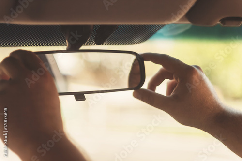 man's hand corrects the rear-view mirror in the car, retro toning