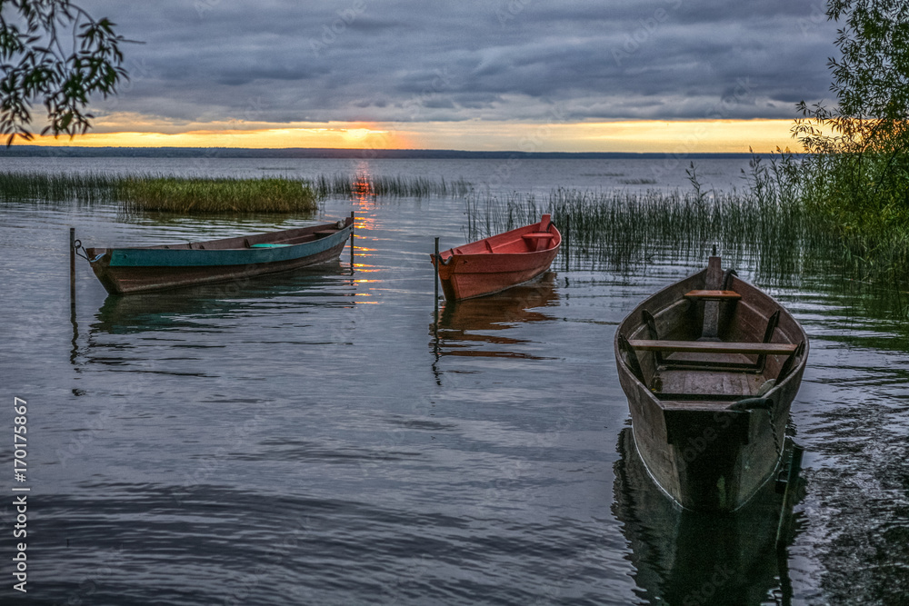 Obraz premium three wooden fishing boats on an autumn decline at the coast of the lake