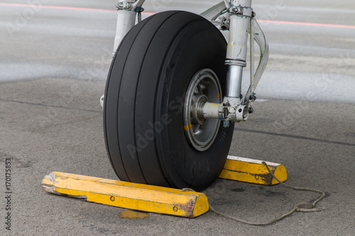 Closeup of aircraft front gear, tire with yellow chocks