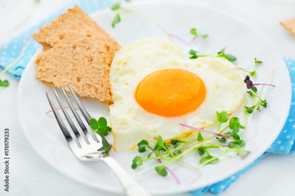 Healthy breakfast. Fried heart shaped egg closeup Healthy breakfast. Fried heart shaped egg closeup