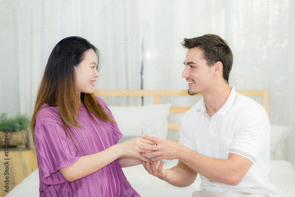 Asian handsome husband takes care about pregnant woman with gives a glass of milk lovely pregnant. Asian handsome husband takes care about pregnant woman with gives a glass of milk lovely pregnant.