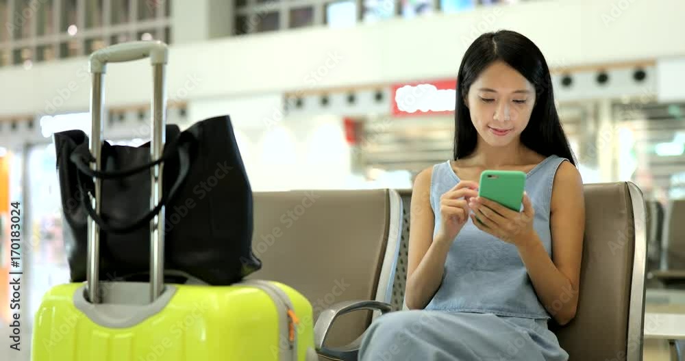 Woman using cellphone in airport Woman using cellphone in airport