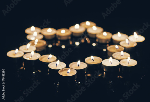 Burning candles in the shape of a star of david on a black background. Bokeh on dark backdrop, shallow depth of field