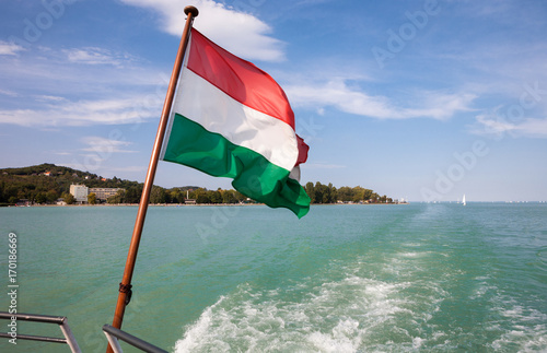 Fototapet Lake Balaton viewed from a ship with the Hungarian flag in the front at Tihany,