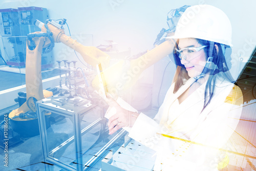 Double exposure of Manufacturing production industrial machine , factory robots arm in smart factory , engineer female using tablet for check monitoring of machine with flare light effect. Blue tone.