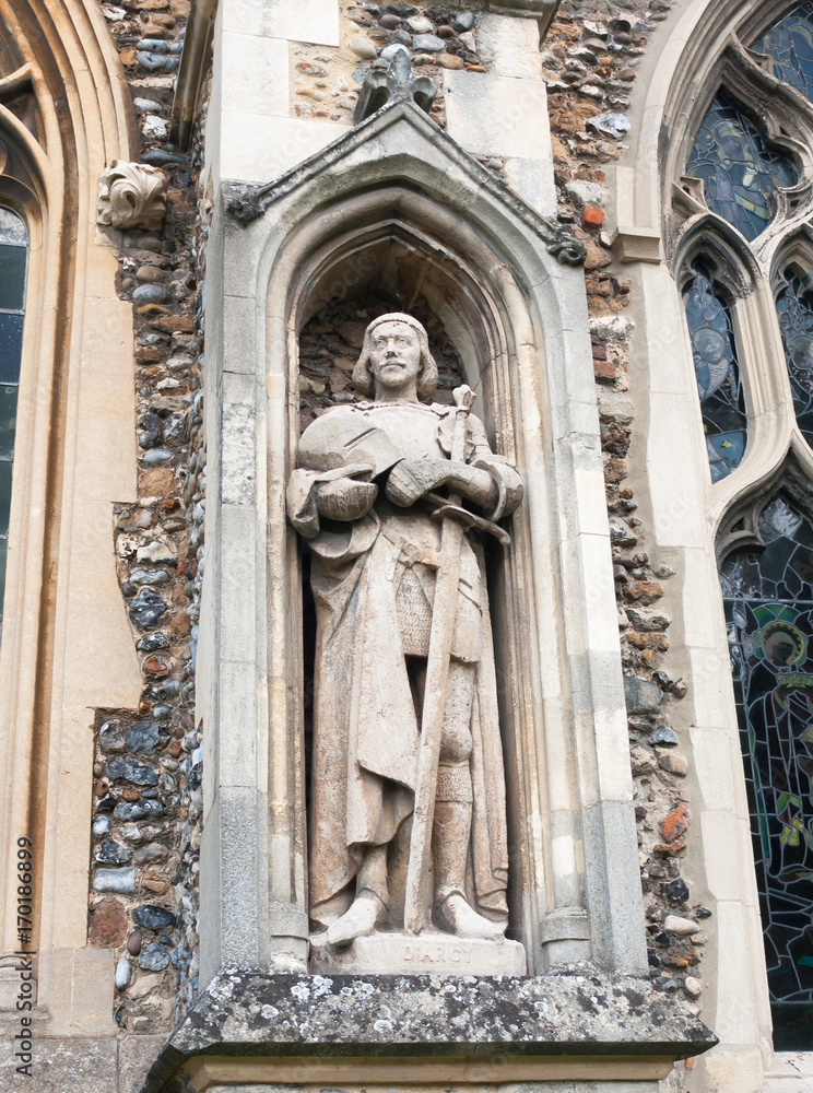 statue of man on the outside of english christian church made of stone