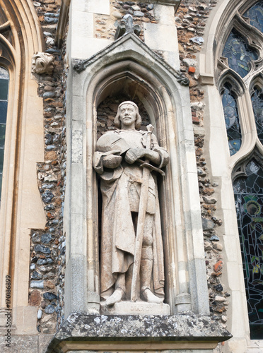 statue of man on the outside of english christian church made of stone