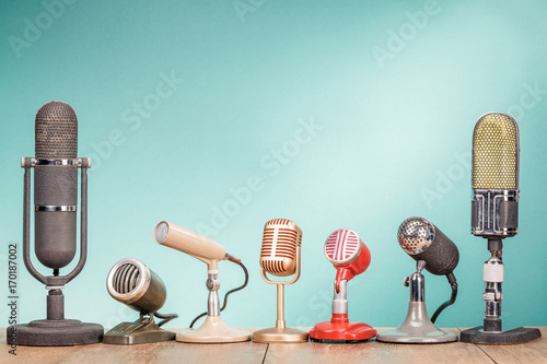 Retro old microphones for press conference or interview on wooden desk front gradient mint green background. Vintage style filtered photo