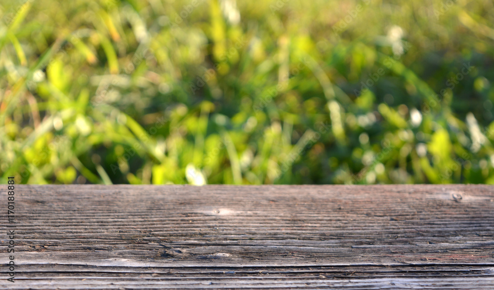 Empty wooden table in the garden with green grass on a day sunny. Blurred background,texture Empty wooden table in the garden with green grass on a day sunny. Blurred background,texture