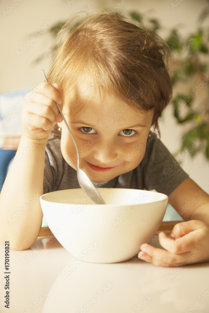 Cute happy little girl having breakfast muesli with milk at home in the kitchen (healthy food, eating, children, childhood concept ) Cute happy little girl having breakfast muesli with milk at home in the kitchen (healthy food, eating, children, childhood concept )