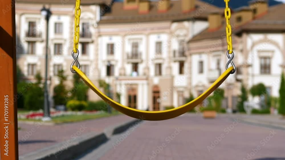 A yellow swing on steel chains pumps the wind on the playground. Slow motion. A yellow swing on steel chains pumps the wind on the playground. Slow motion.