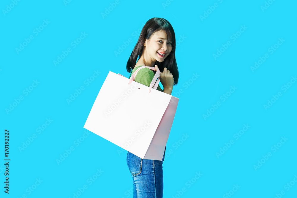 Woman wearing green shirts holding shopping bags in the blue background. Woman wearing green shirts holding shopping bags in the blue background.