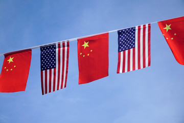 USA and China flags hanging under blue sky