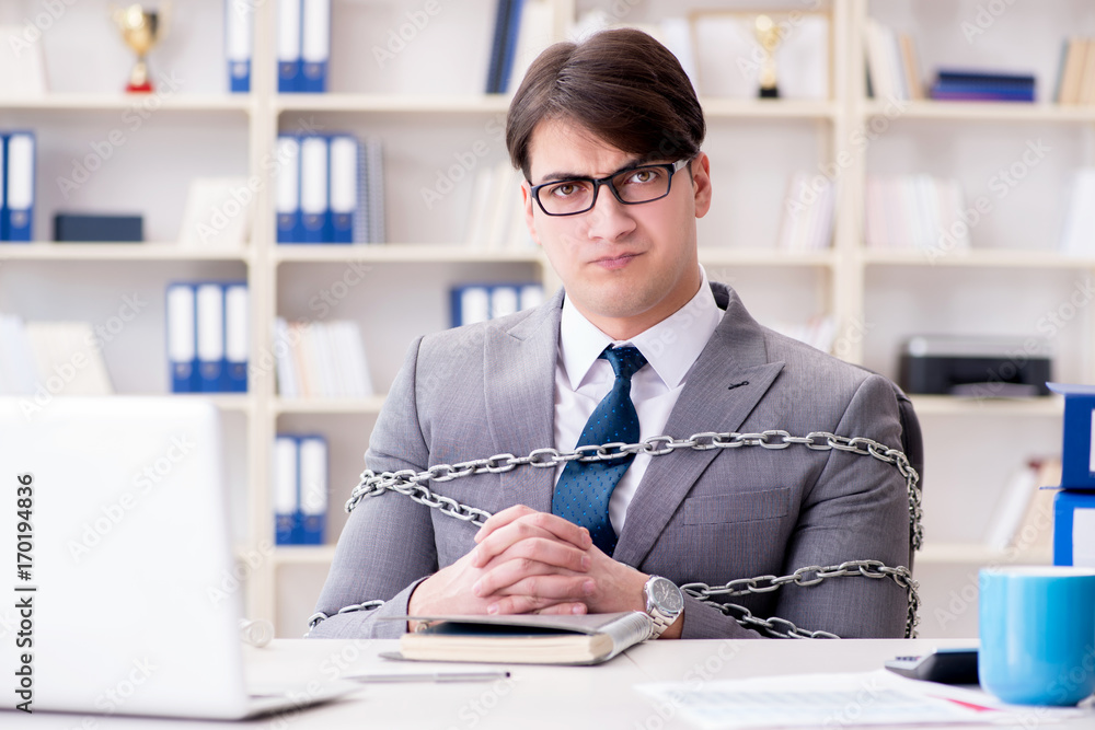 Businessman tied with chains to his work Businessman tied with chains to his work