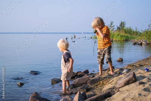 Obraz na płótnie two brothers kids play near lake with binoculars, Uveldy, the Urals, Russia, w salonie