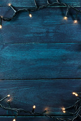 Fairy lights on a dark wooden texture, holiday background