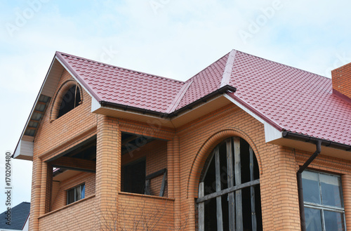 Brick house with attic balcony and metal roof construction.