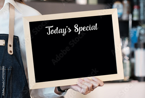 Foto Hand holding blank Today's special board  over blur cafe background, copy space