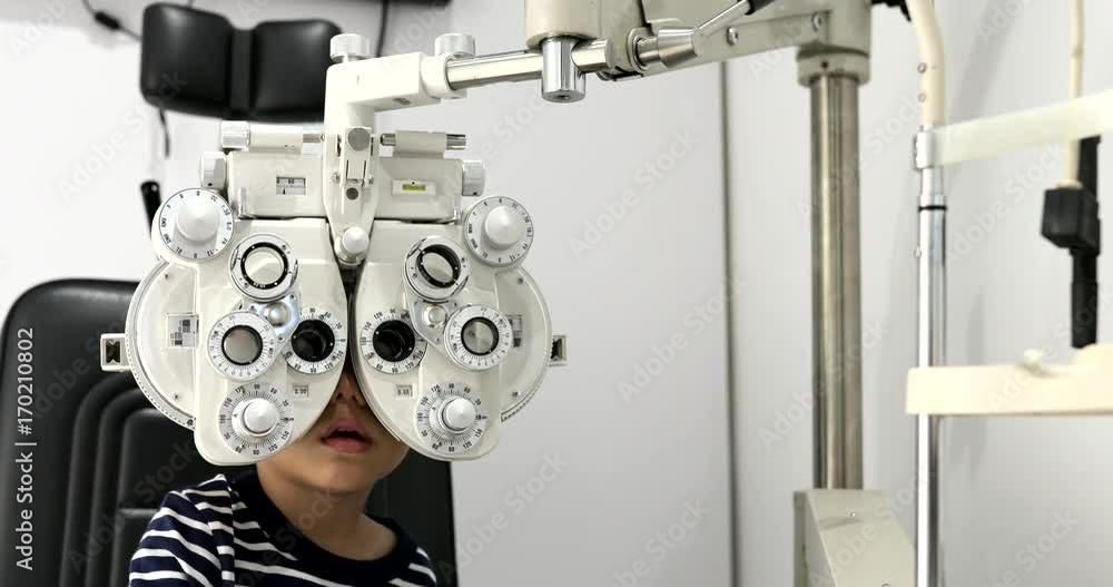 Little boy undergoing eye test with phoropter Little boy undergoing eye test with phoropter
