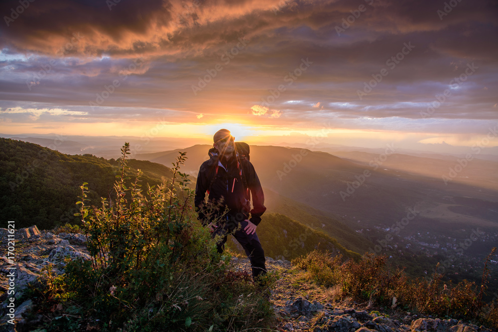 Amazing sunset on a mountain top - man with alpine equipment enjoying the breathtaking view under the stormy sky
