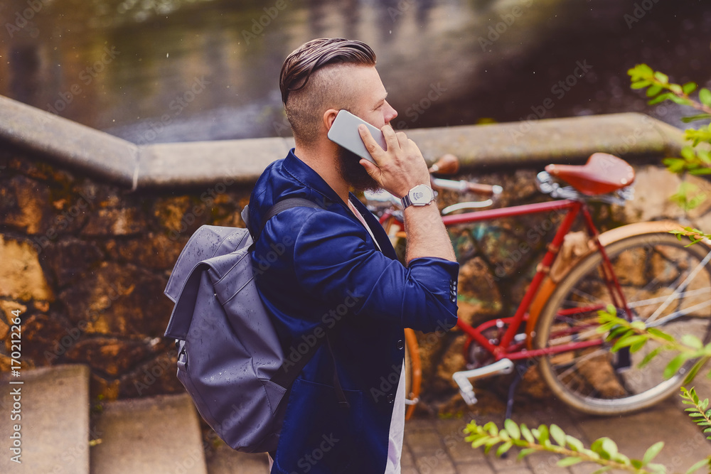 Casual bearded male in a park talks by smart phone. Casual bearded male in a park talks by smart phone.