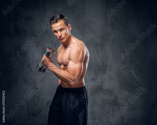 Shirtless male holds a set of dumbbells.