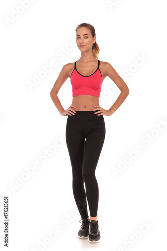 full body picture of a young fitness woman standing with hands on waist on white background