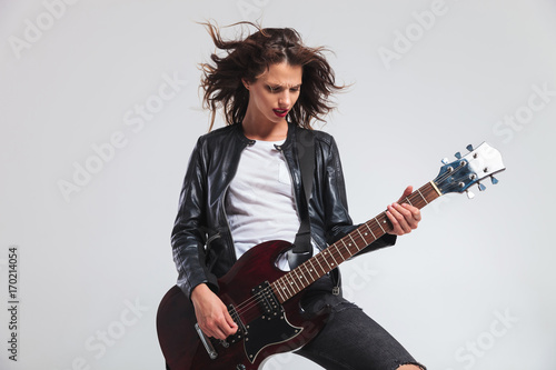 passionate woman guitarist with flying hair playing