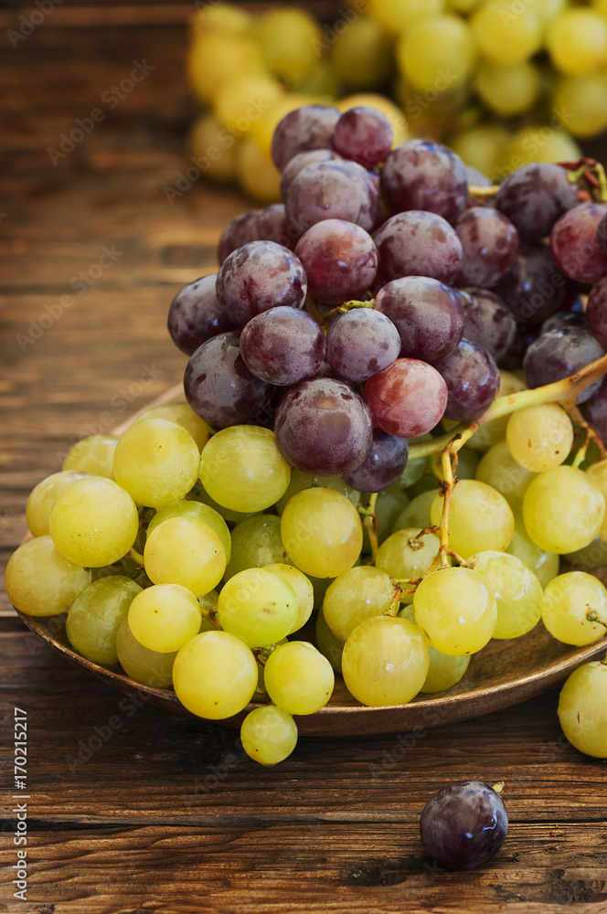 Red and yellow grape on the wooden table, selective focus Red and yellow grape on the wooden table, selective focus