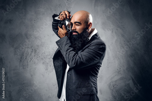 Professional photographer in a suit shooting with a compact DSLR camera.
