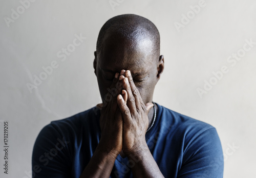 Black man with hands covered his face feeling worried photo