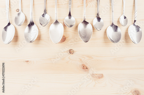 Collection rustic empty spoons on beige wood background. Mock up for designer, restaurant menu, advertising.