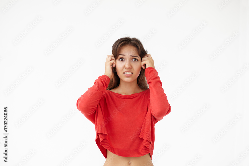 Waist up shot of young female dressed casually having worried and frustrated look, holding hands on her head and looking at camera with terror and panic. Human emotions, feelings and life perception Waist up shot of young female dressed casually having worried and frustrated look, holding hands on her head and looking at camera with terror and panic. Human emotions, feelings and life perception