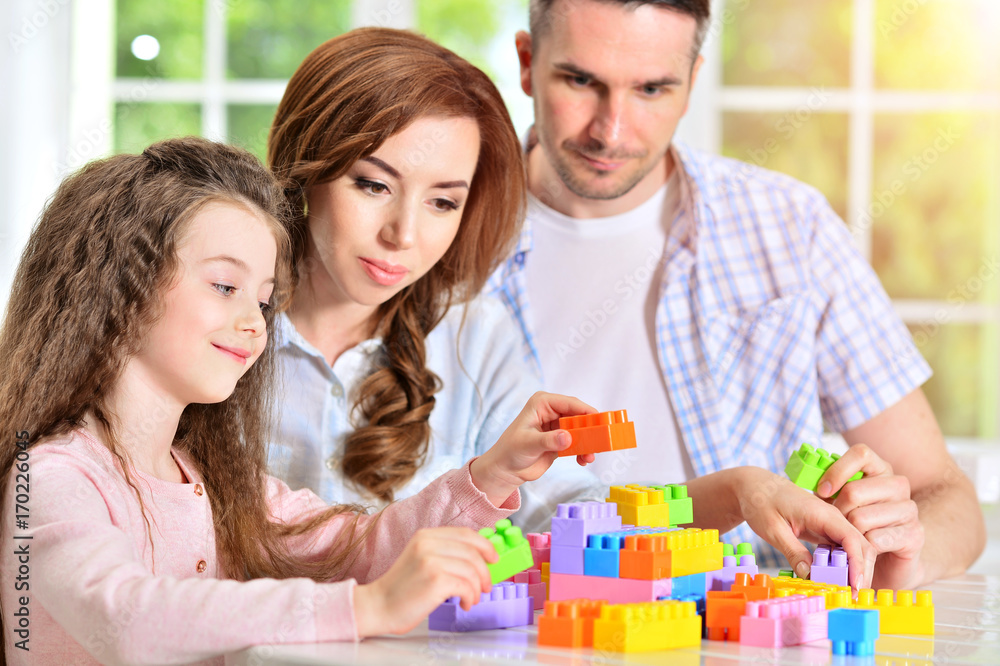 parents and daughter playing with plastic blocks parents and daughter playing with plastic blocks