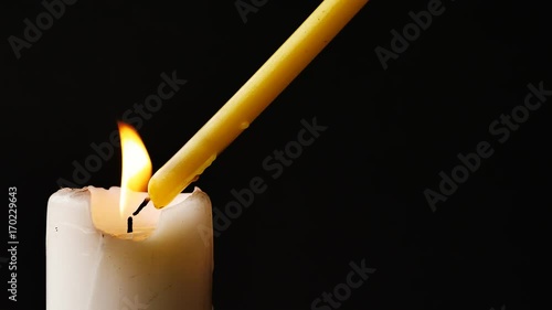 Close up shot of a candle being lit on a black background. 