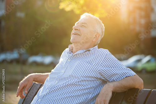Wall Mural Outdoor portrait of senior man who is enjoying sun.