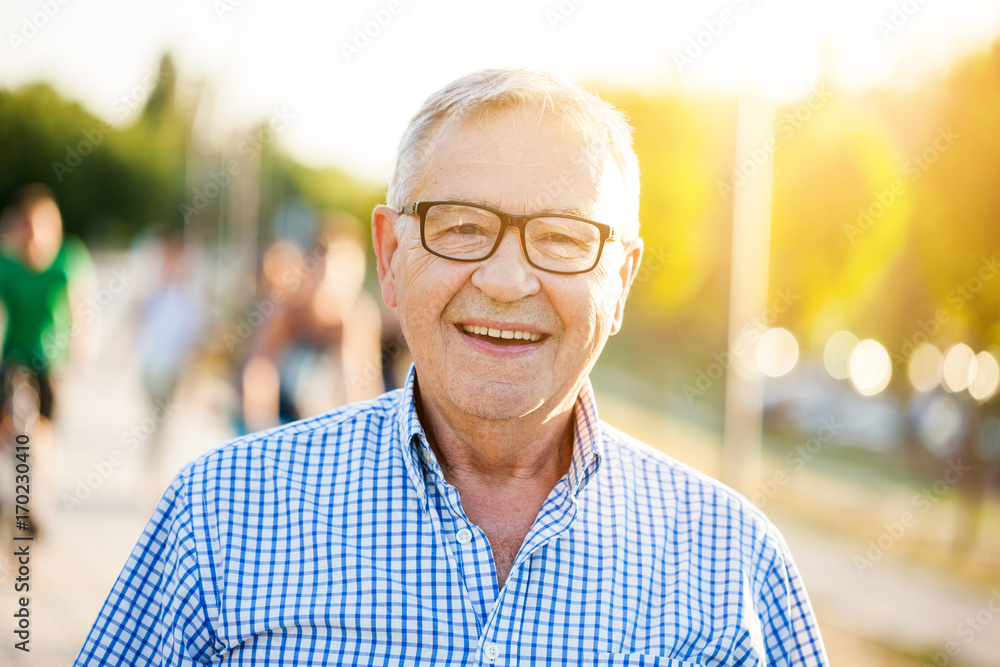 Outdoor portrait of happy senior man who is looking at camera and smiling. - obrazy, fototapety, plakaty 