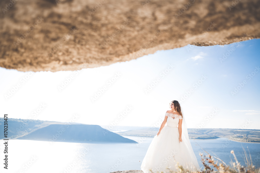 Pretty lady, bride posing in a wedding dress near sea on sunset Pretty lady, bride posing in a wedding dress near sea on sunset