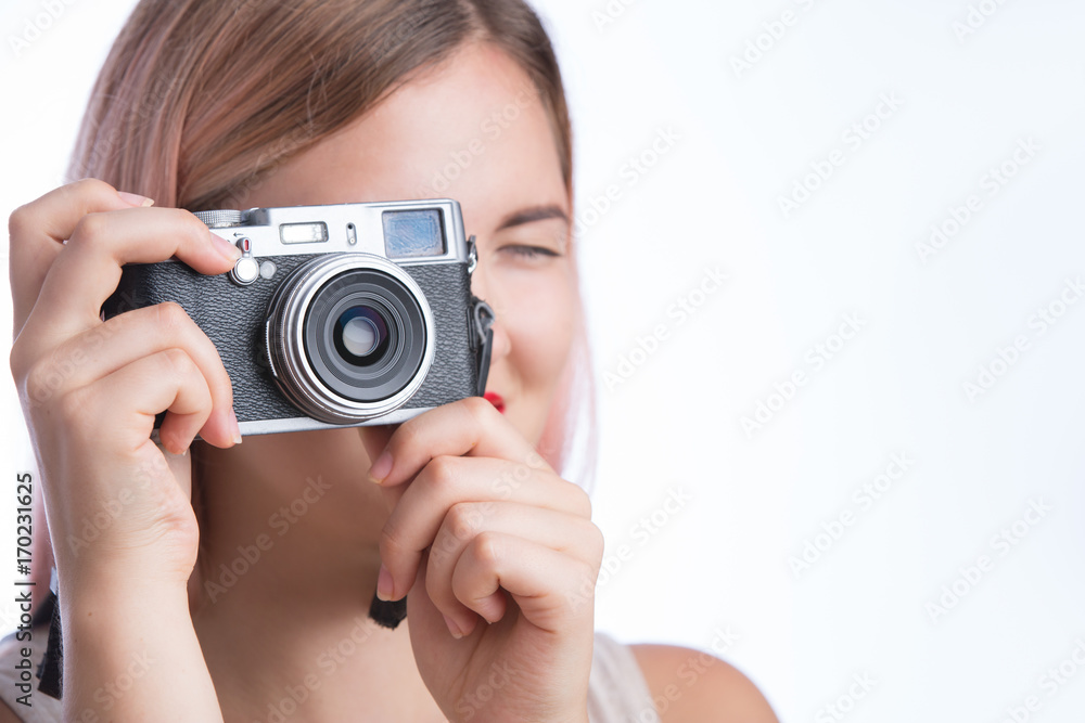 Young stylish girl taking photo with retro camera and looking at camera on white background Young stylish girl taking photo with retro camera and looking at camera on white background