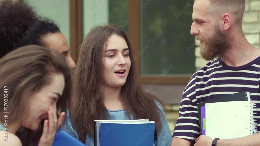 Close up view of students talking in front of university. Young multiethnic friends before classes in college. Close up view of students talking in front of university. Young multiethnic friends before classes in college.