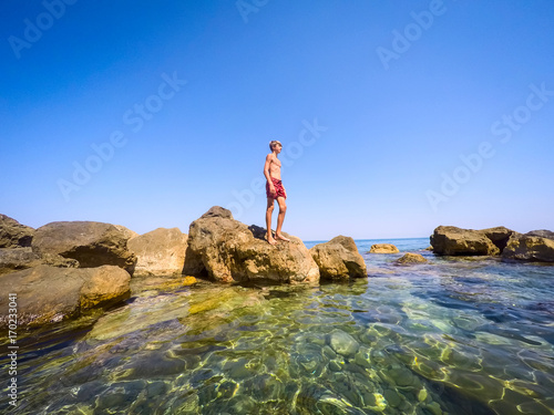 teenager standing on the rocks at seaside - summertime - Sicily mediterranean sea