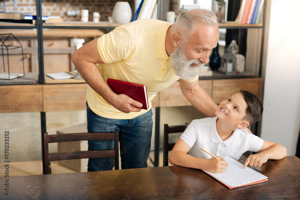 Obraz premium Little schoolboy asking grandfathers advice on homework